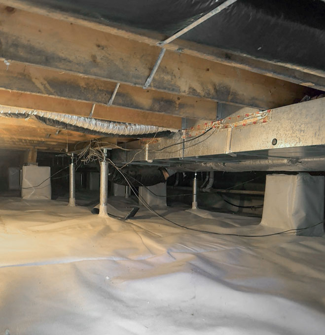 An encapsulated crawl space with a clean white vapor barrier lining the floor and piers beneath dark, mold-stained subfloor wood joists and ductwork.